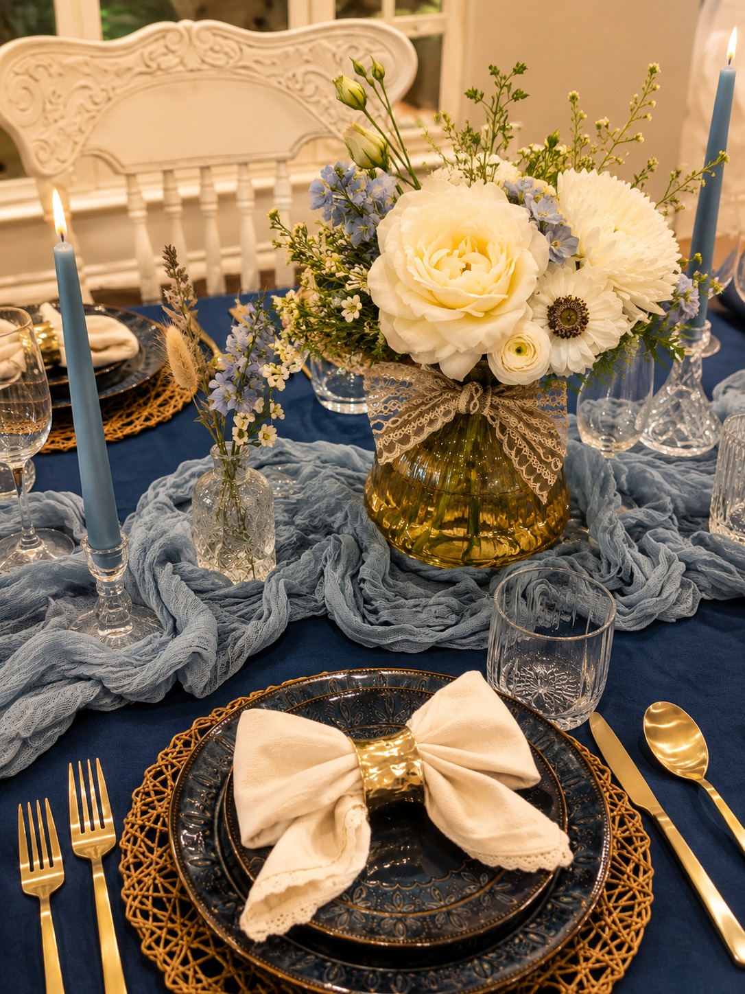 Navy table with a linen bow napkin at a gold ring beside a floral centerpiece and dusty blue runner